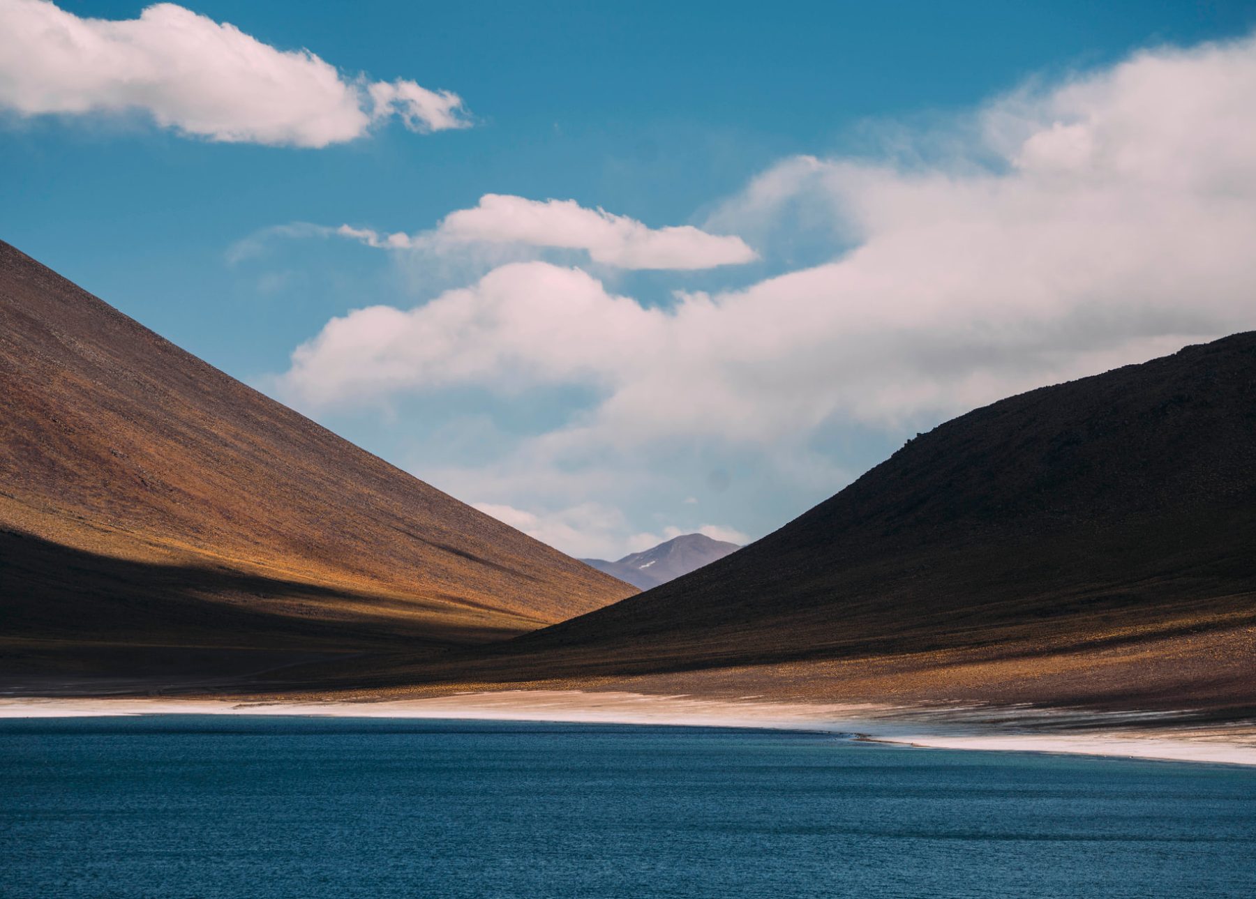 Lagoa de águas azuis entre encostas douradas do altiplano