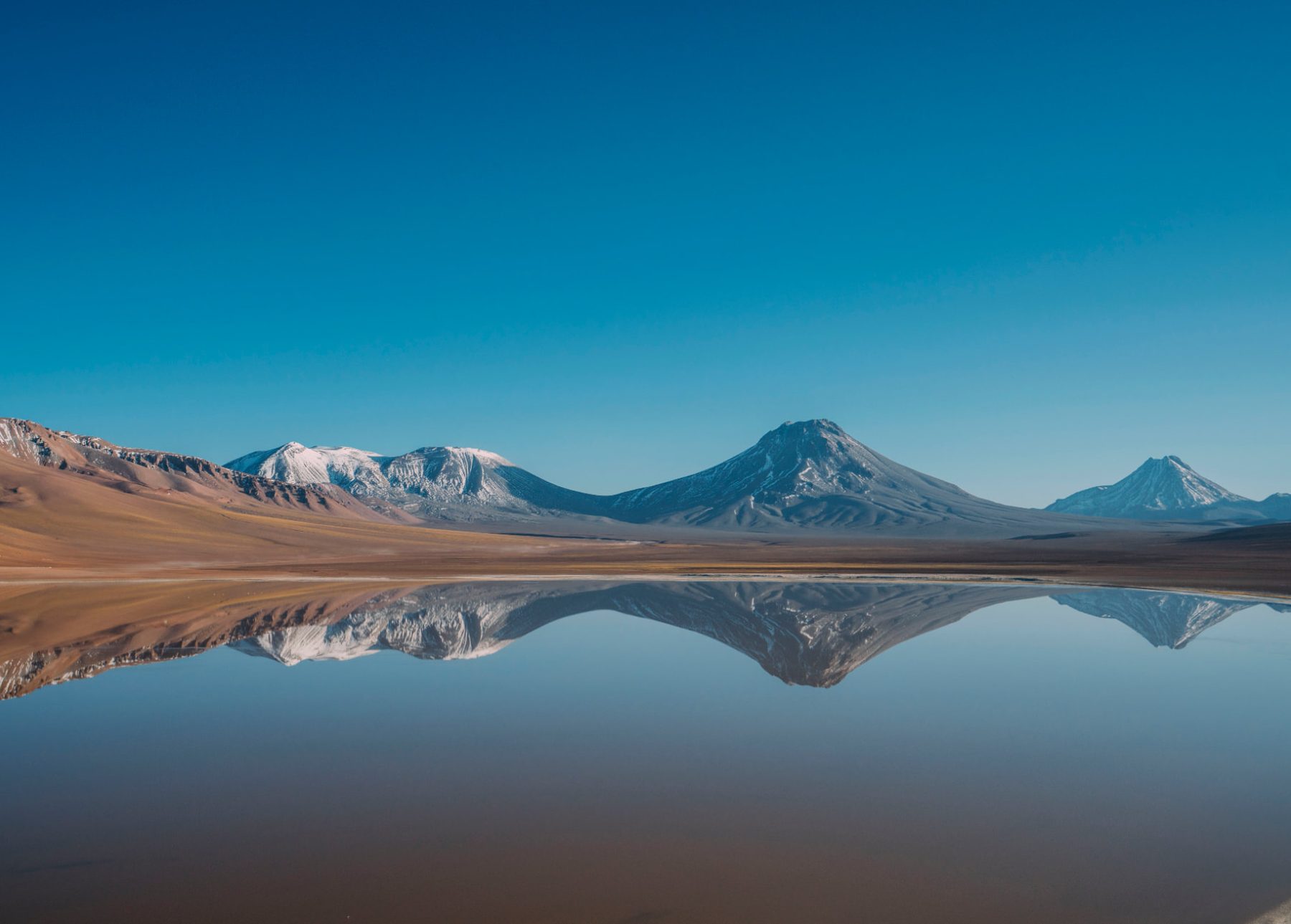 Montanhas refletidas na superfície espelhada de uma lagoa altiplânica