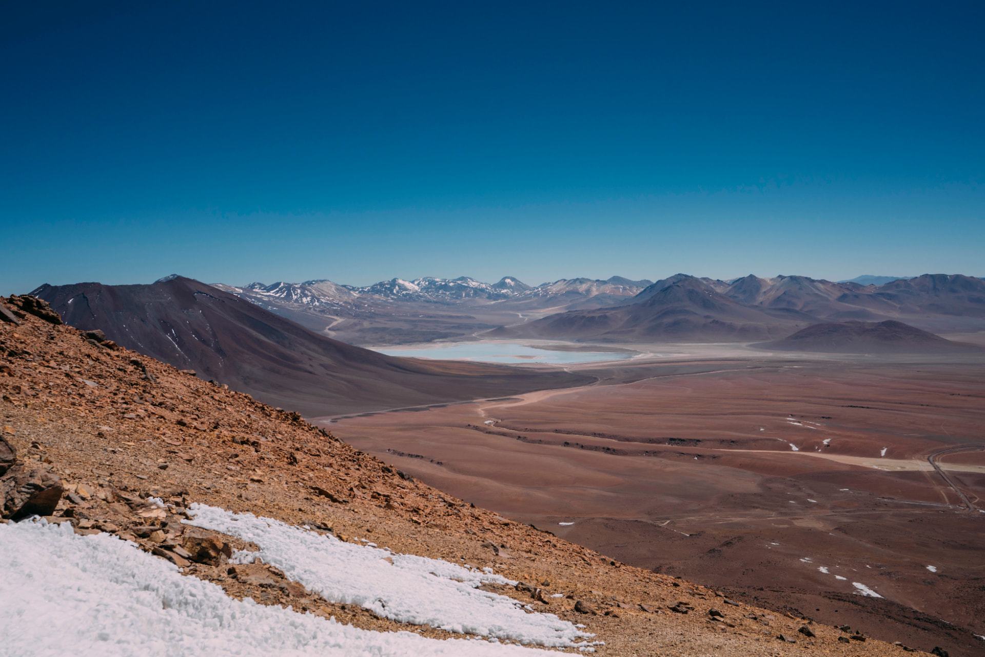 Vista do alto do altiplano com salar e cordilheira nevada ao fundo