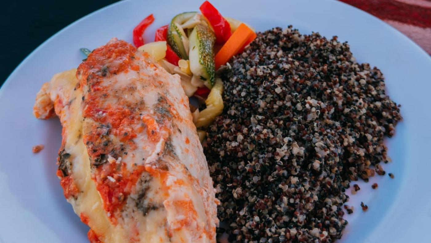 Prato com peixe gratinado, quinoa e legumes servido ao ar livre